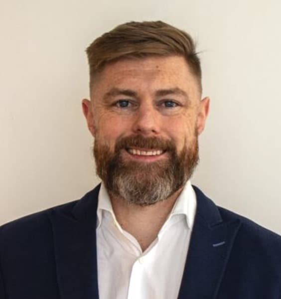 Adult white man with a beard smiling looking at the camera