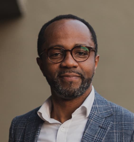 Middle aged black man with glasses smiling looking at the camera